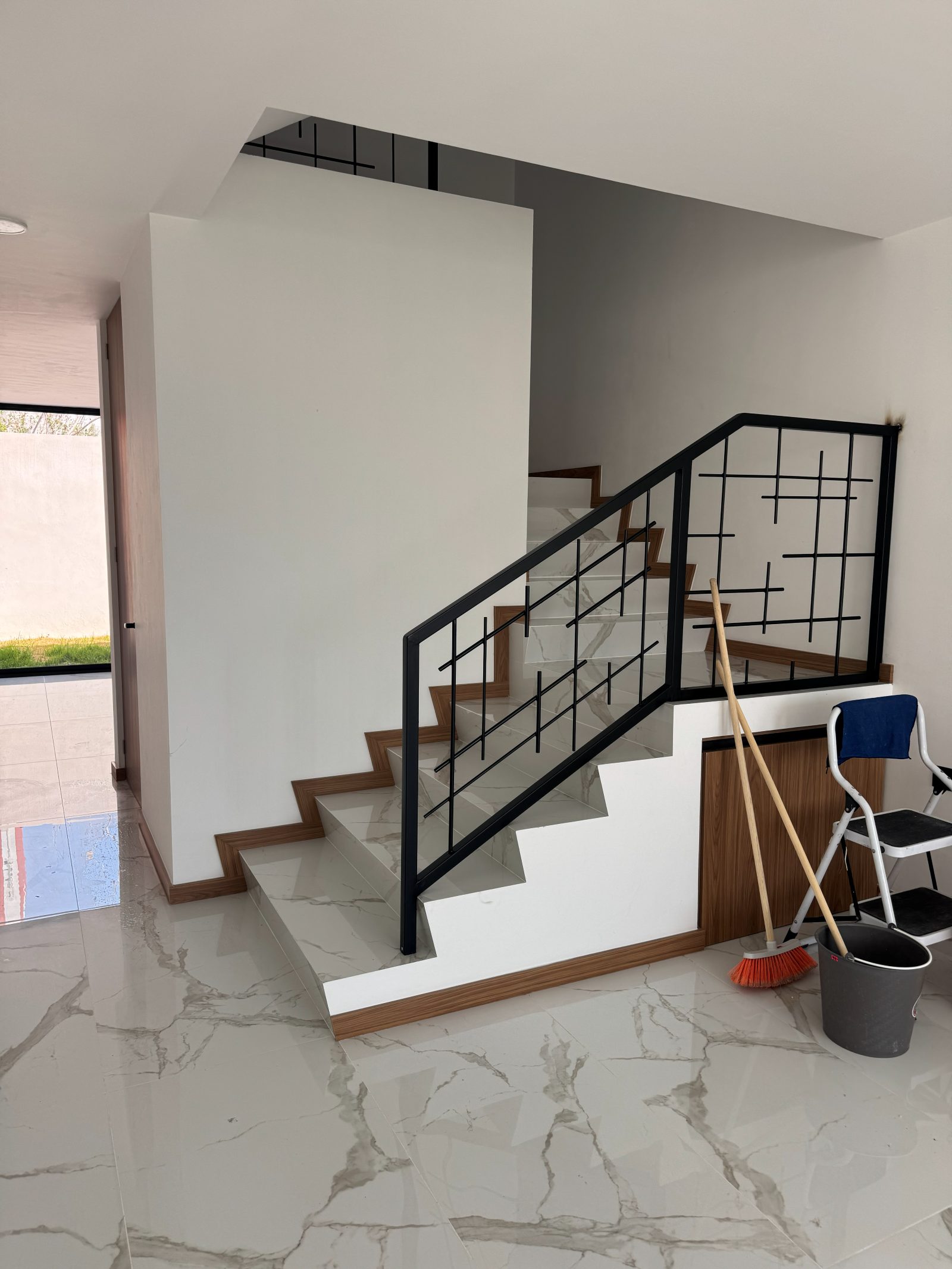 Escalera de hierro forjado sobre piso de mármol Calacatta